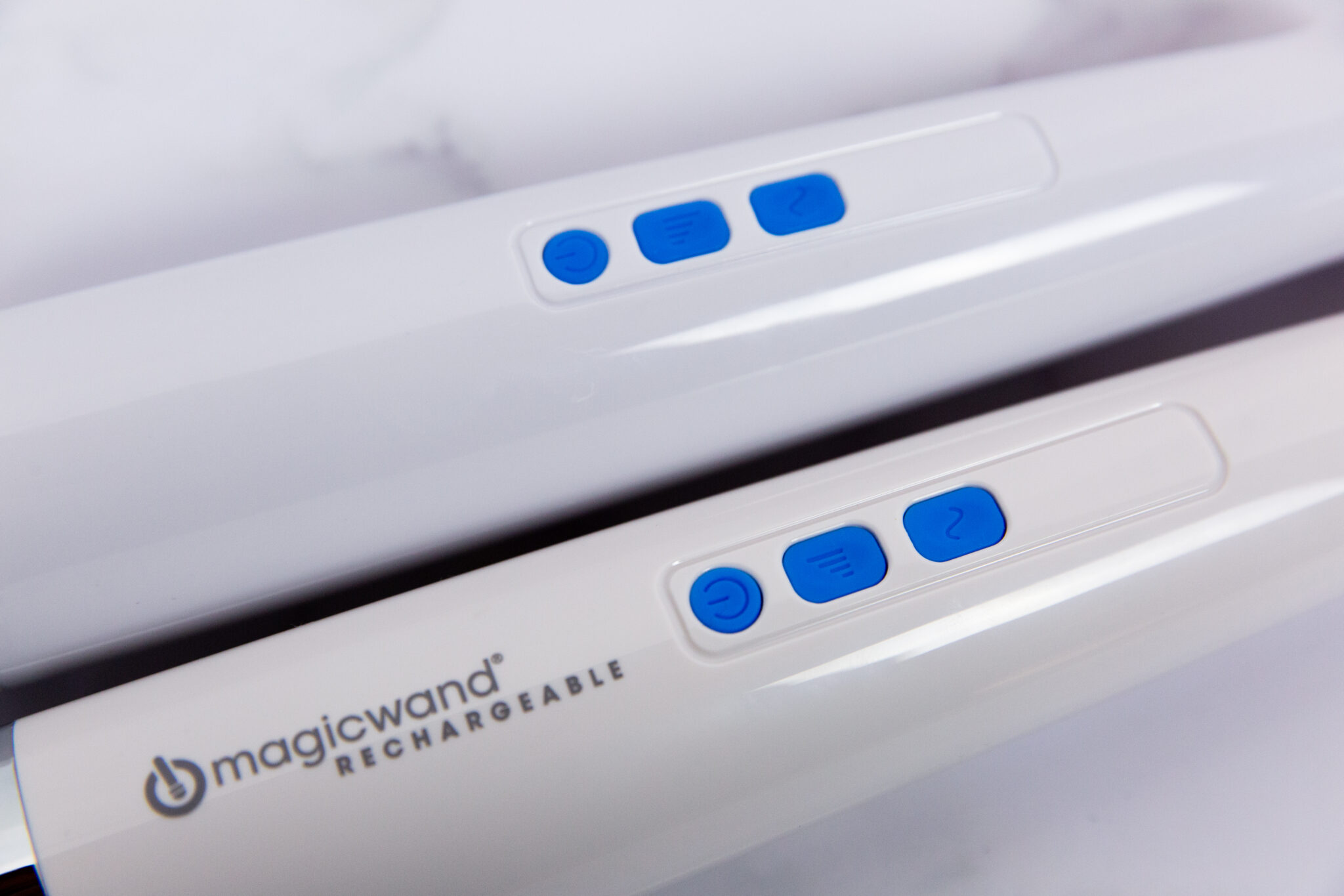 The Magic Wand (bottom) alongside the fake (top), showing the differences of their bodies and blue buttons.