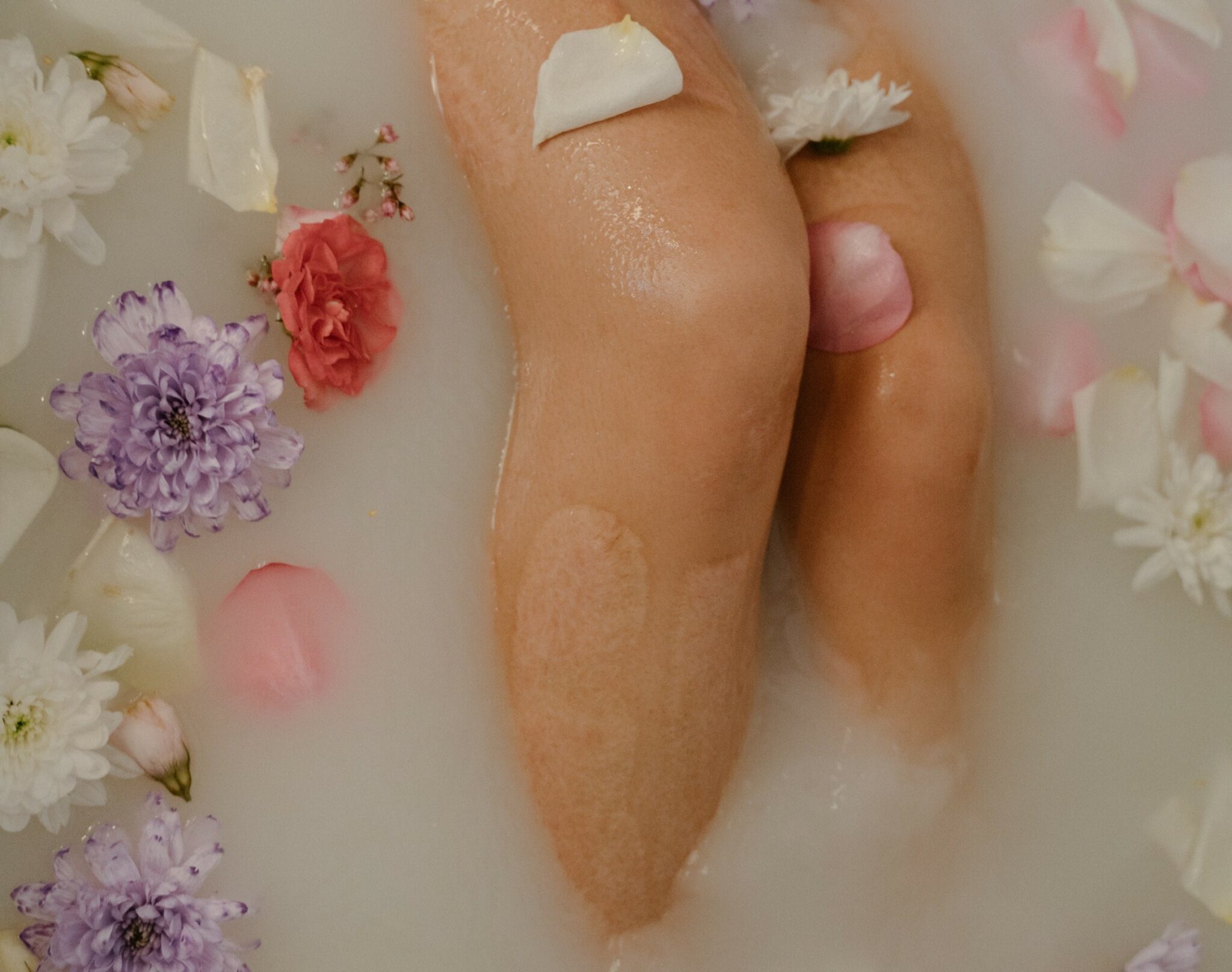 Legs stretched out in a milky bath filled with flowers.