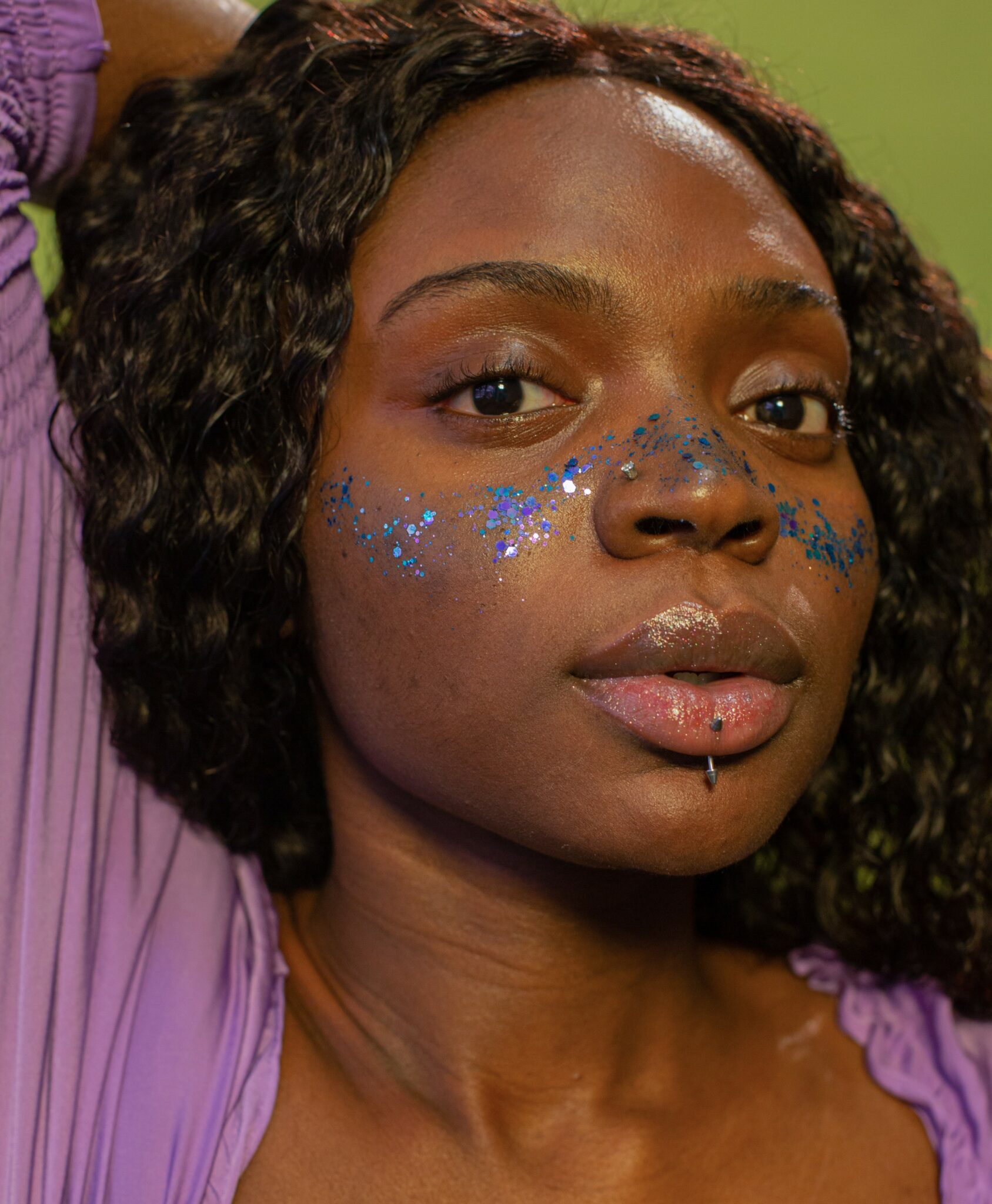 A close-up of a Black woman's face with glitter on her cheekbones.