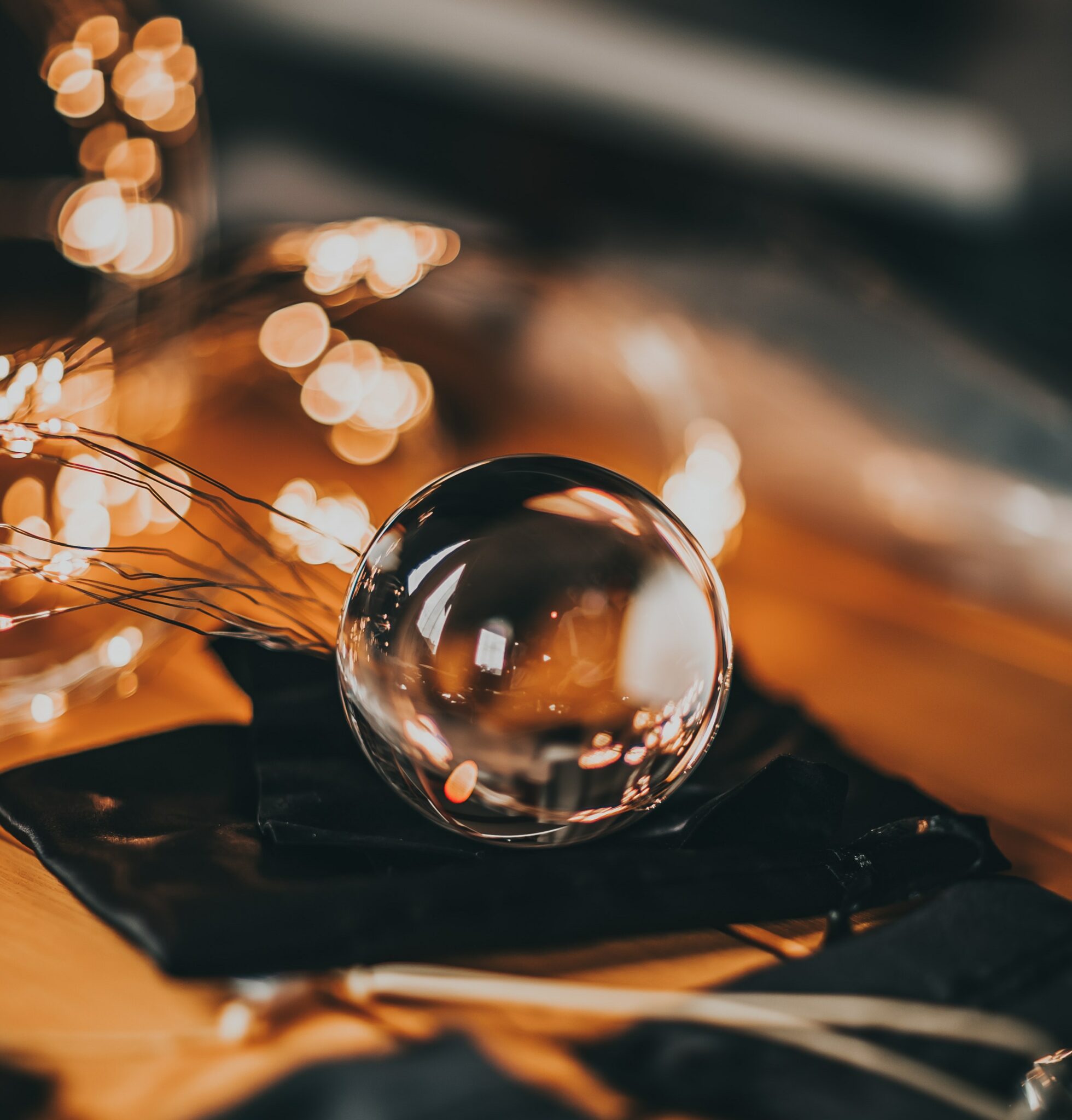 A glass Ben Wa ball in front of a string of yellow fairy lights.