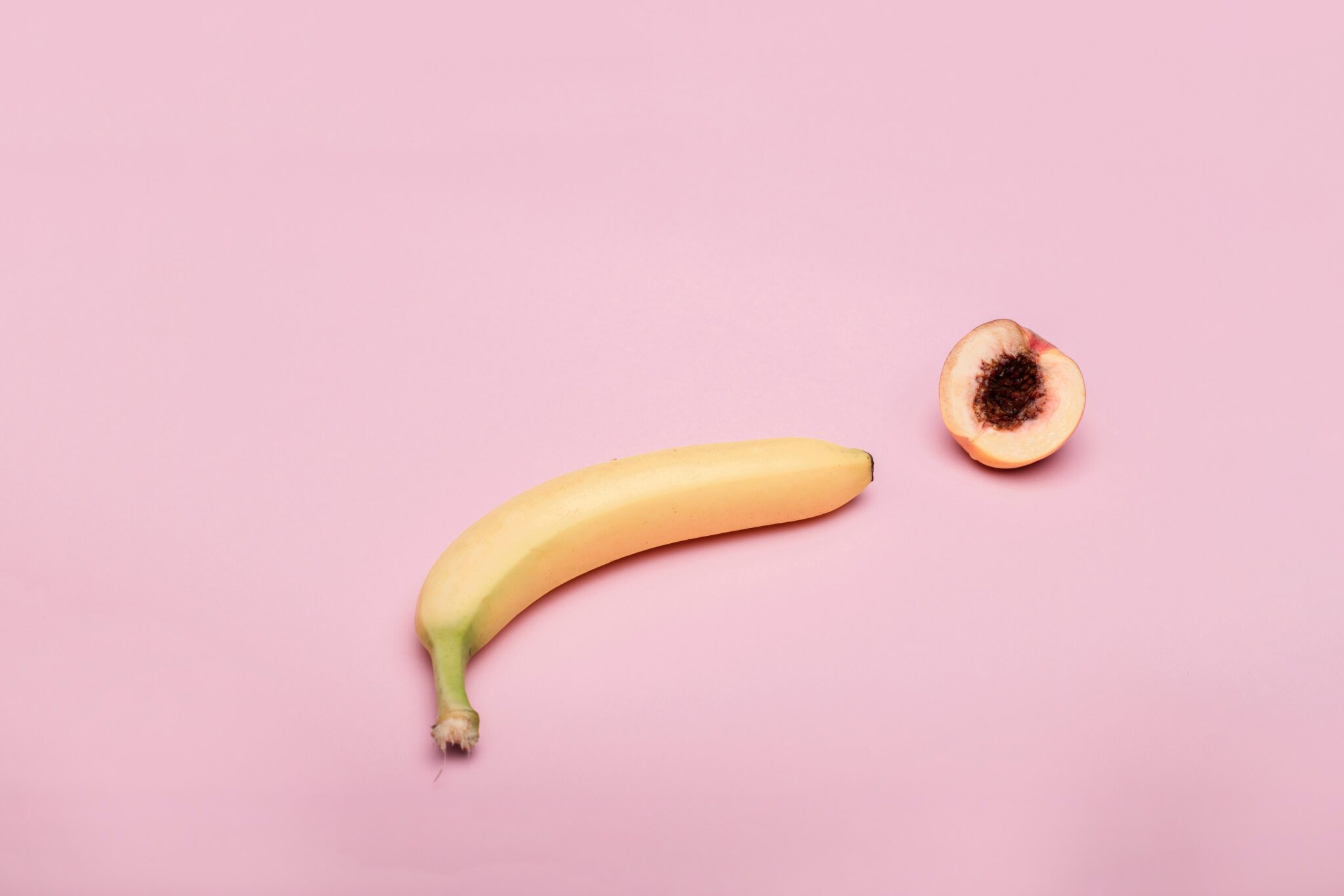 A banana laying flaccid next to an opened fruit.