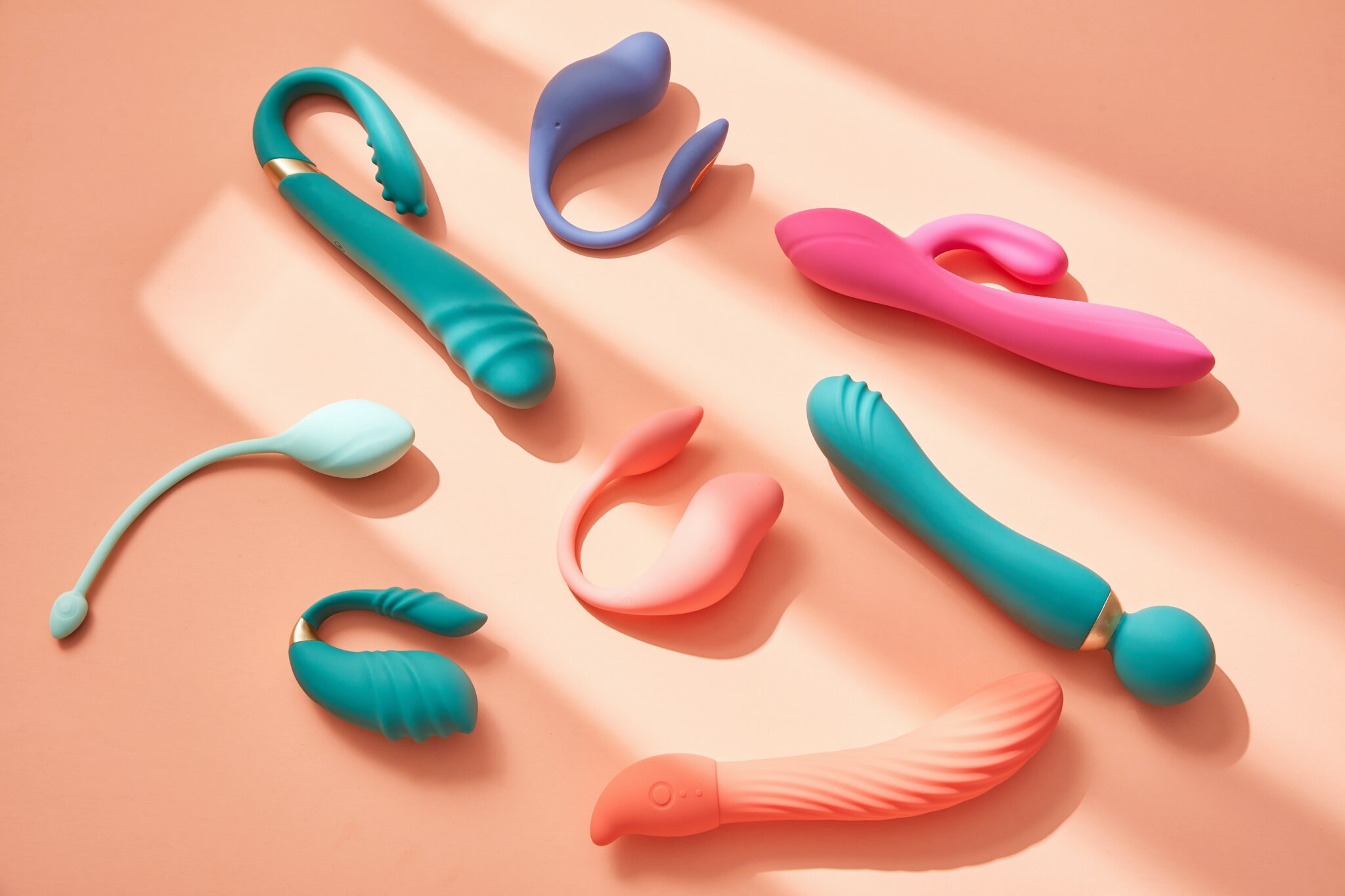 A collection of sex toy vibrators in a colorful array over an orange background.