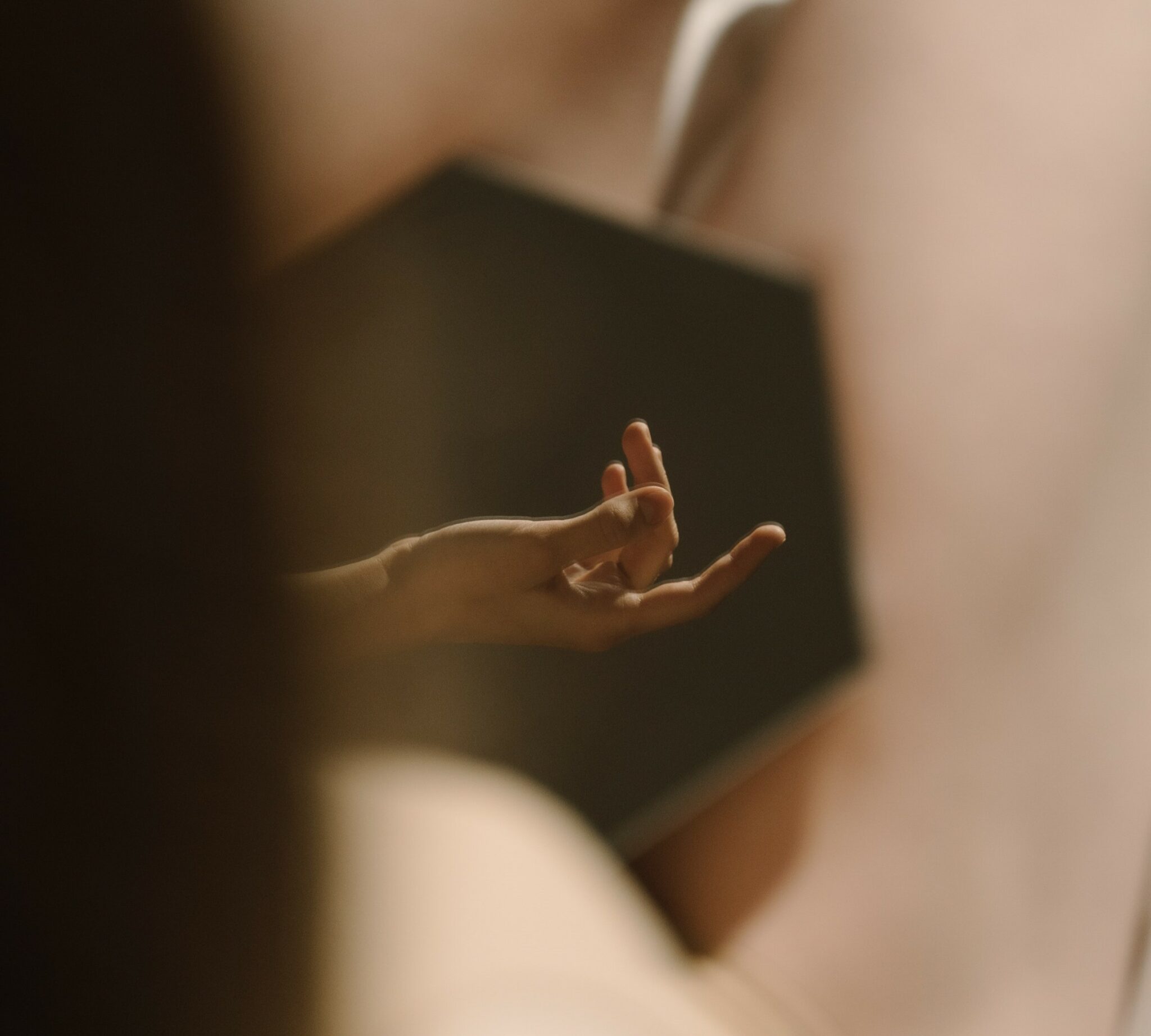 A woman's hand reflected in a mirror sitting a naked woman's lap.