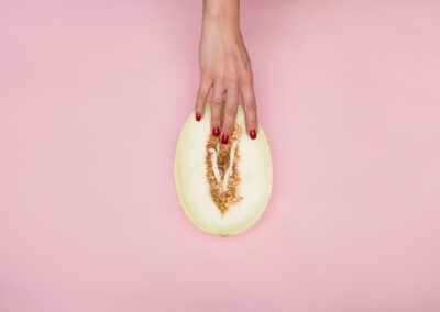 Woman's hand fingering a cantaloupe.