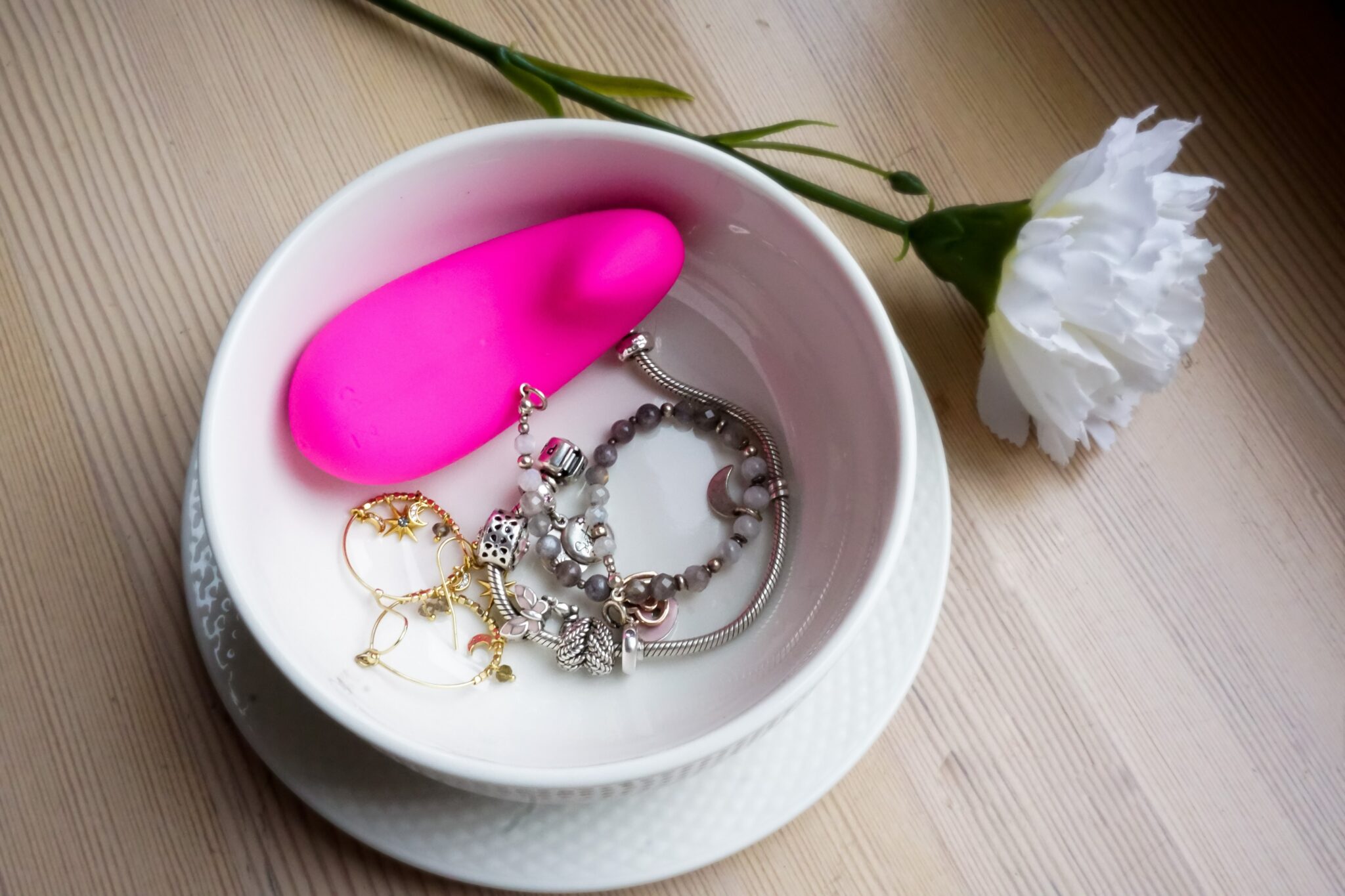 A pink vibrator in a bowl of jewelry