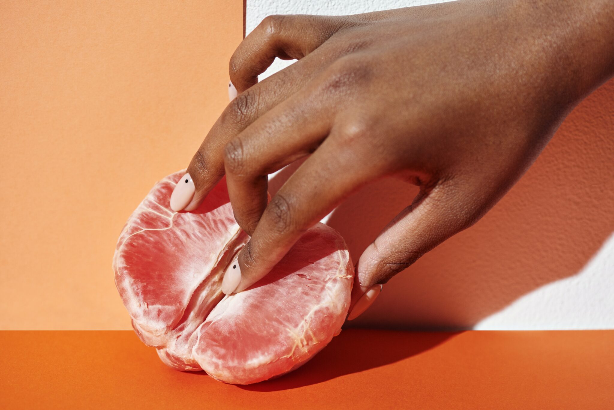 A woman's hand fingering the middle of a sliced orange.