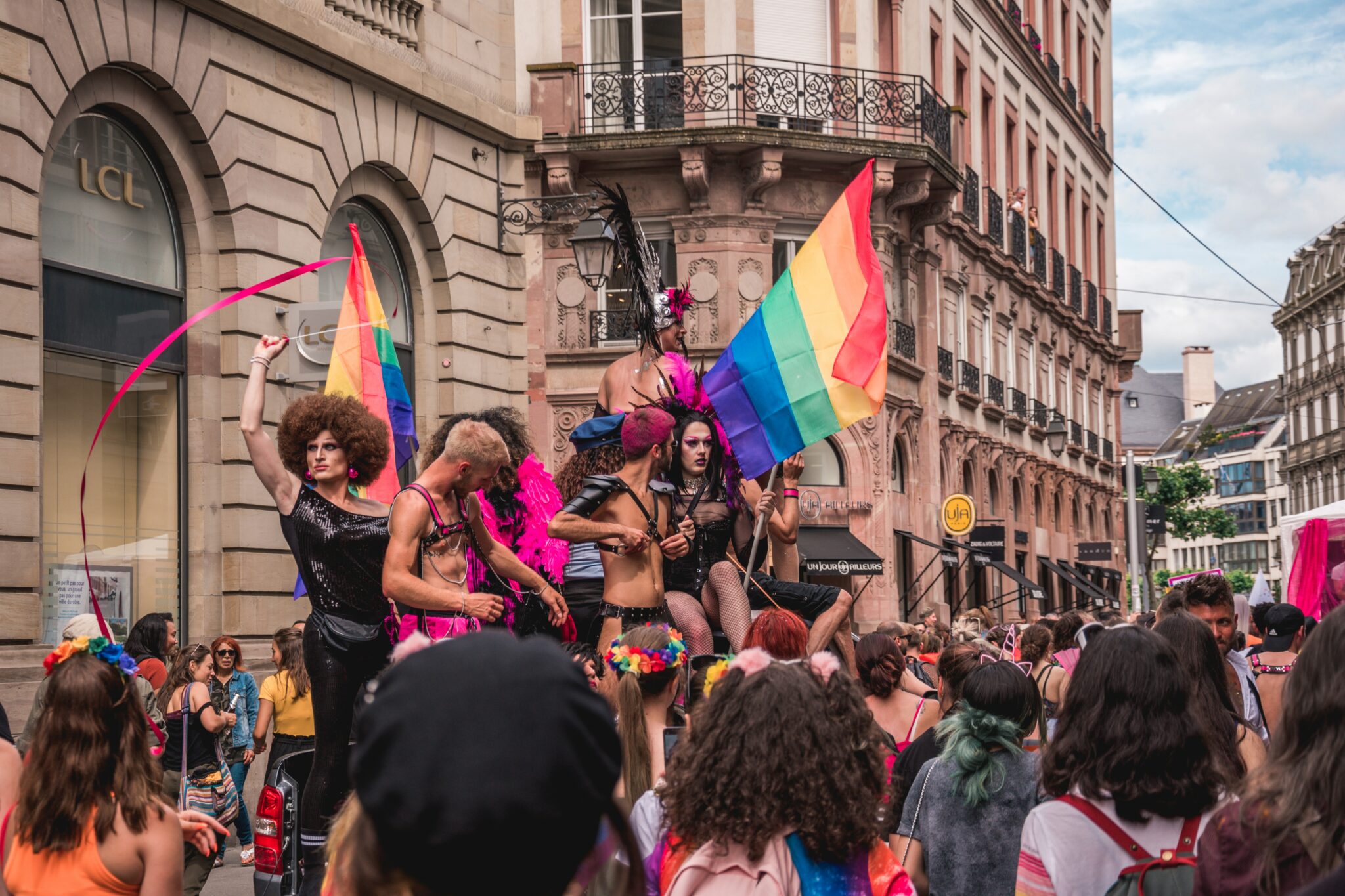 Drag queens standing on a float in a Pride parade.