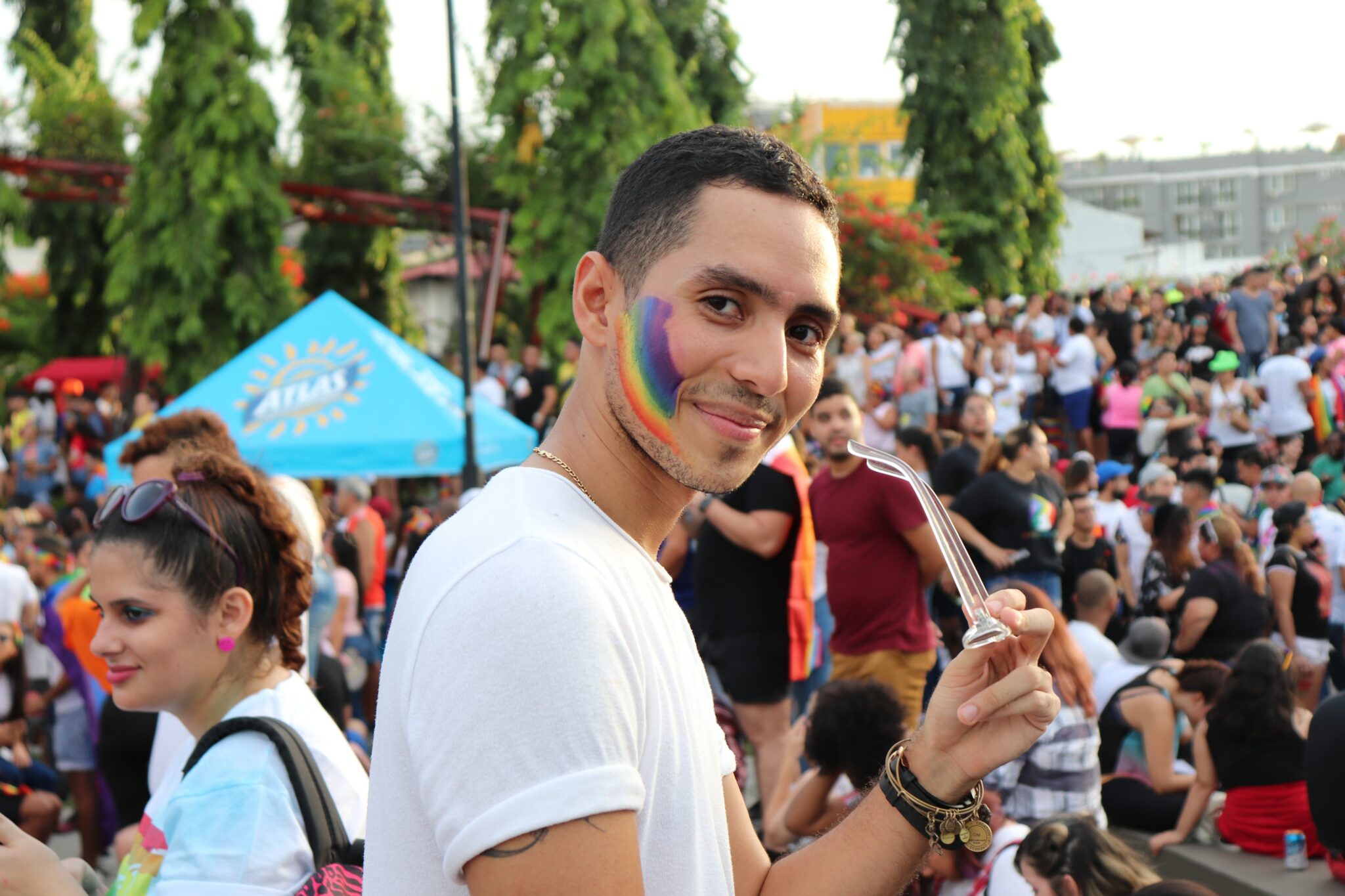 A man at a Pride event with a rainbow painted on his cheek.