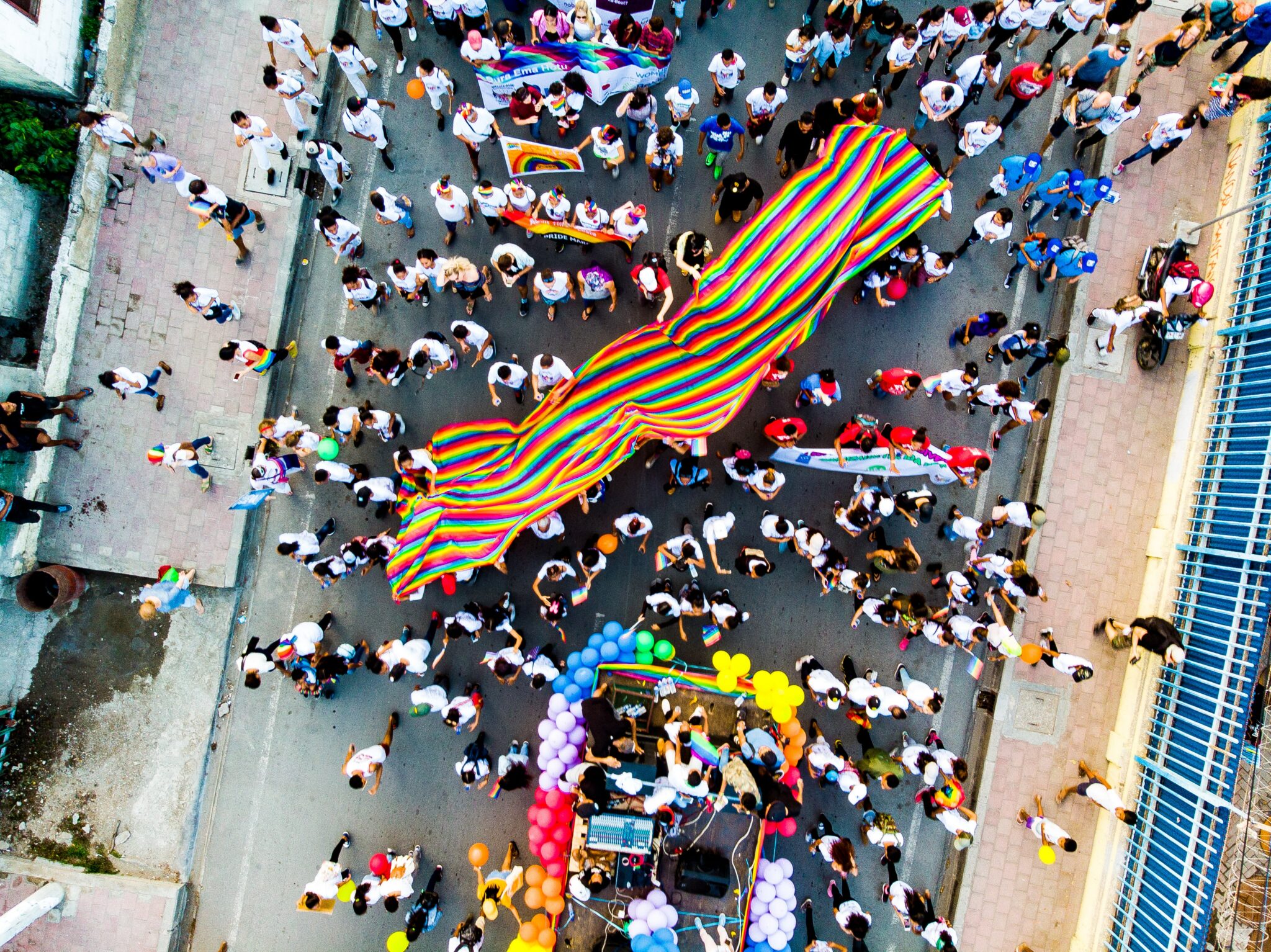 A view looking down at a Pride parade, showing all of the marchers' colors and flags.
