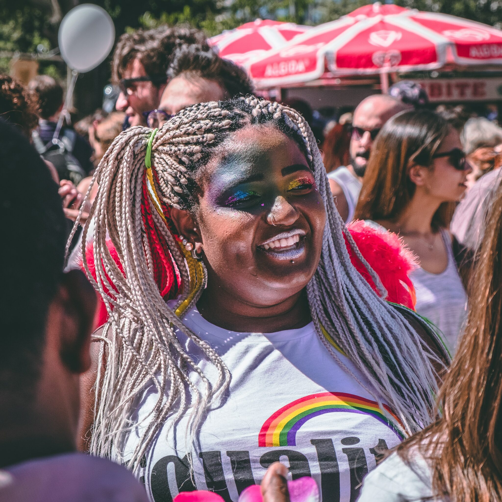 A woman at a Pride event with rainbow makeup on her eyes.