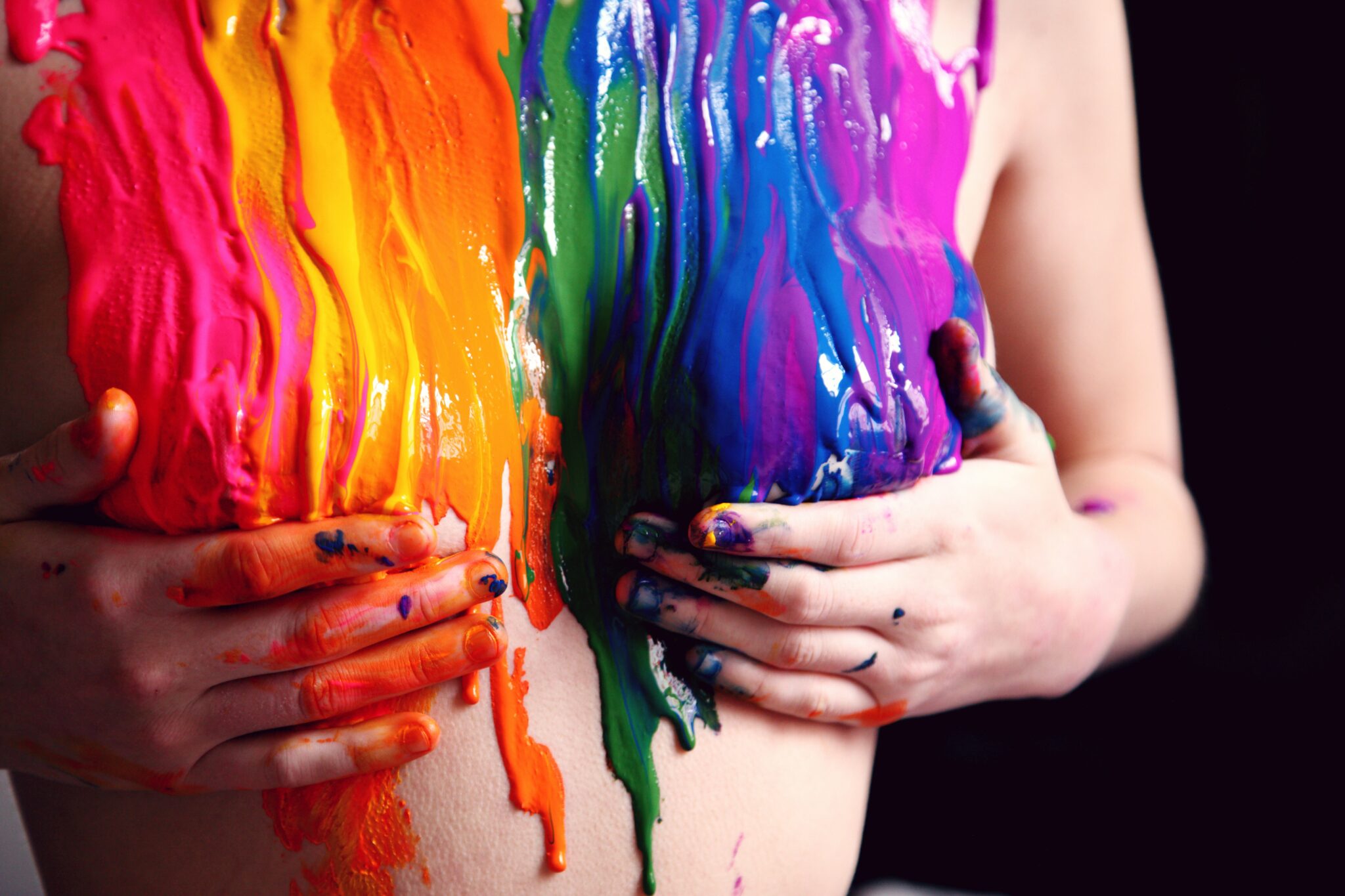 Rainbow paint dripping down a woman's chest.
