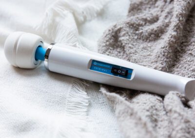 A full image of the vibrator, showing its white body, blue accents, and rounded head.