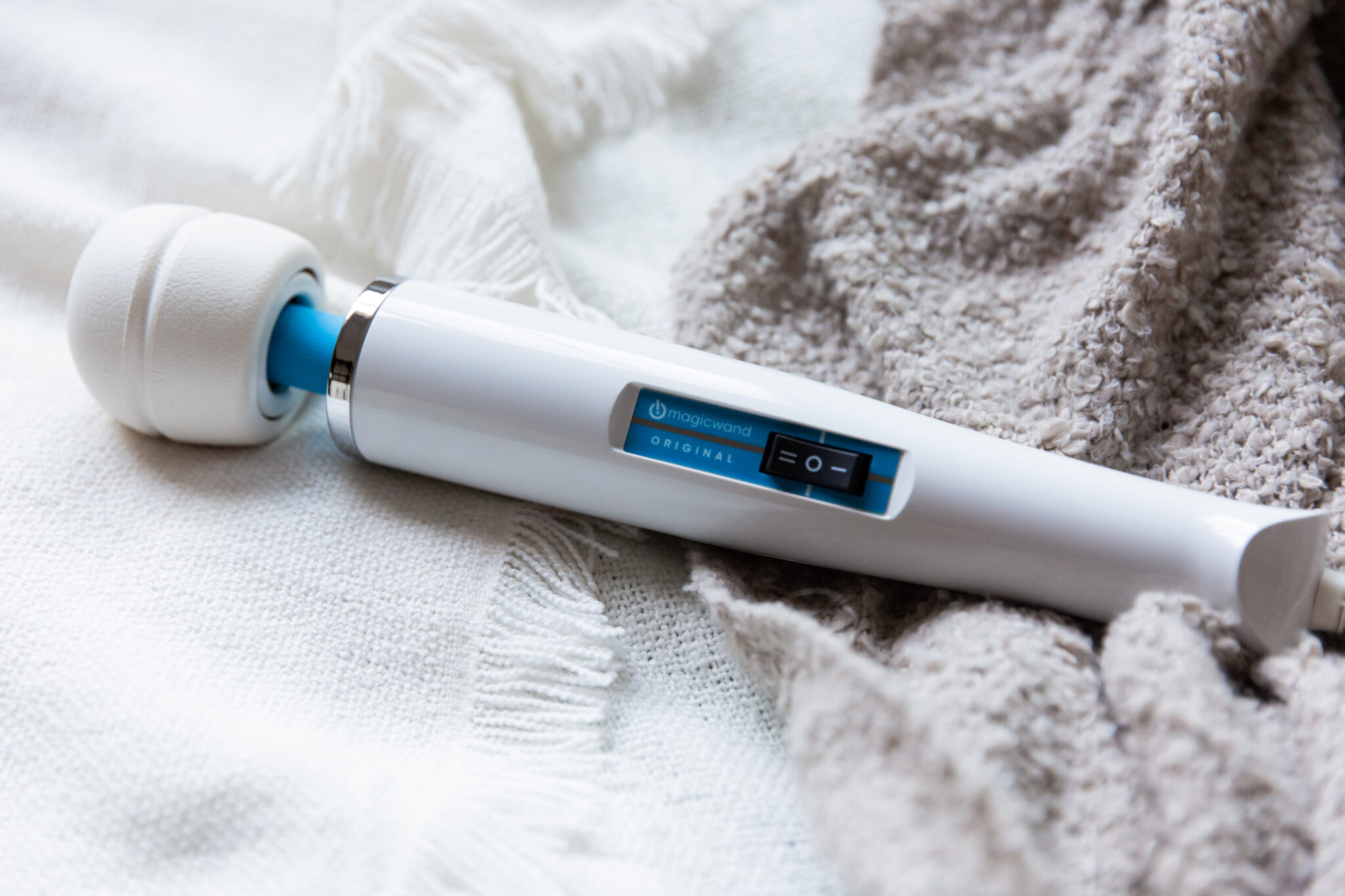 A full image of the vibrator, showing its white body, blue accents, and rounded head.