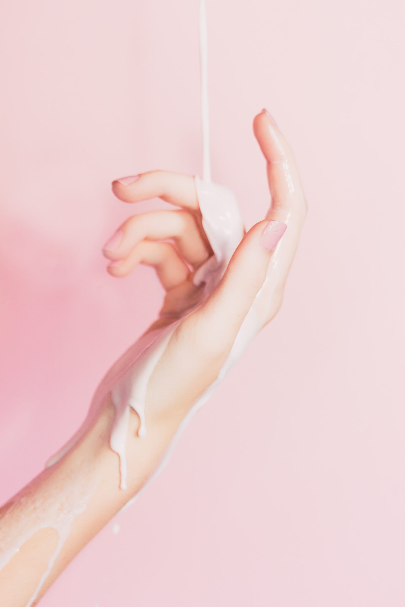 A woman's hand dripping in white liquid.