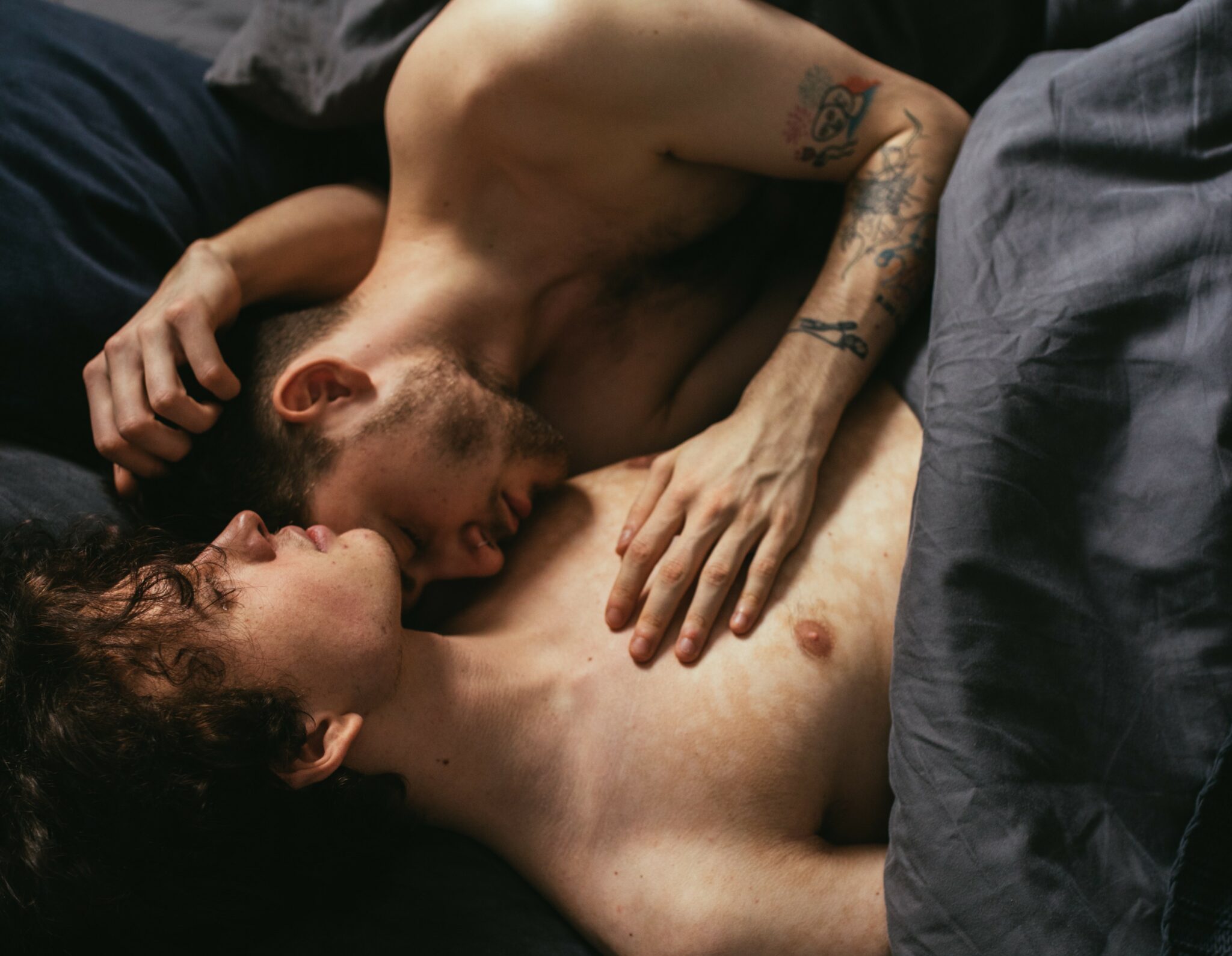 A gay couple cuddling in bed.
