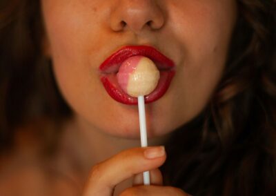 Woman sucking on a lollipop with red lips.