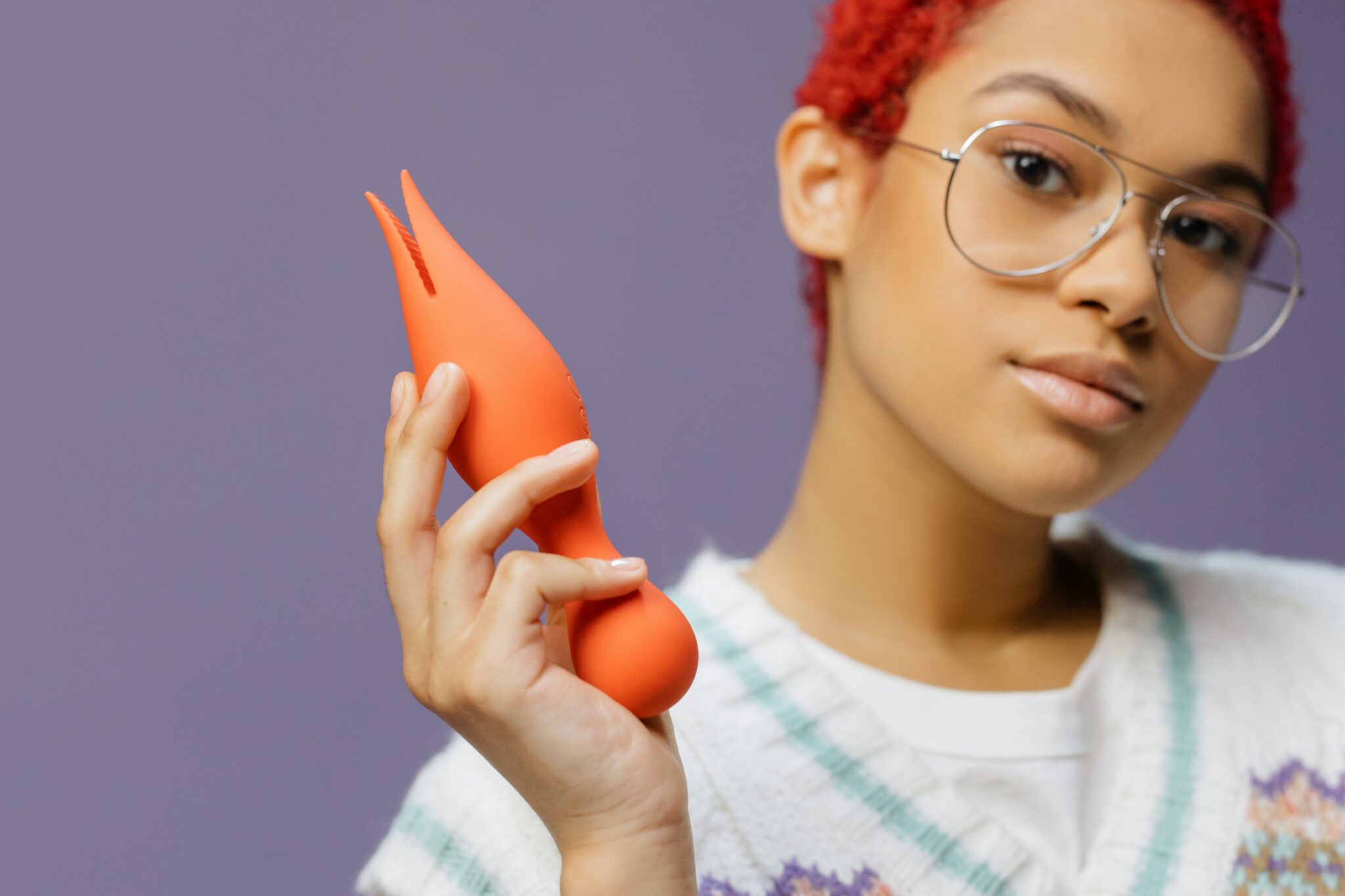 A woman holding an orange female sex toy.