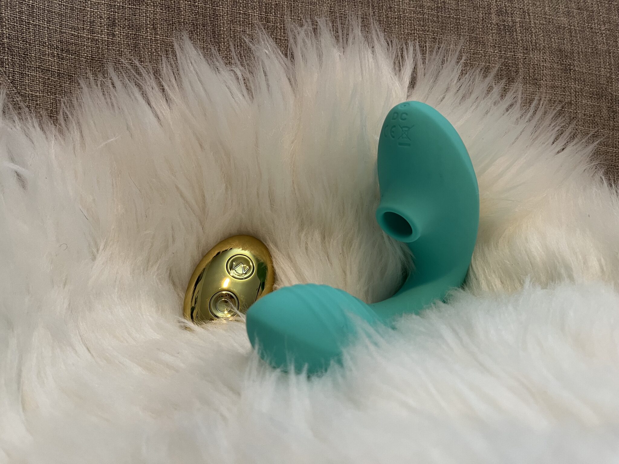 The Tracy's Dog OG Pro 2 clitoral sucking vibrator is teal with gold accents and a golden remote.