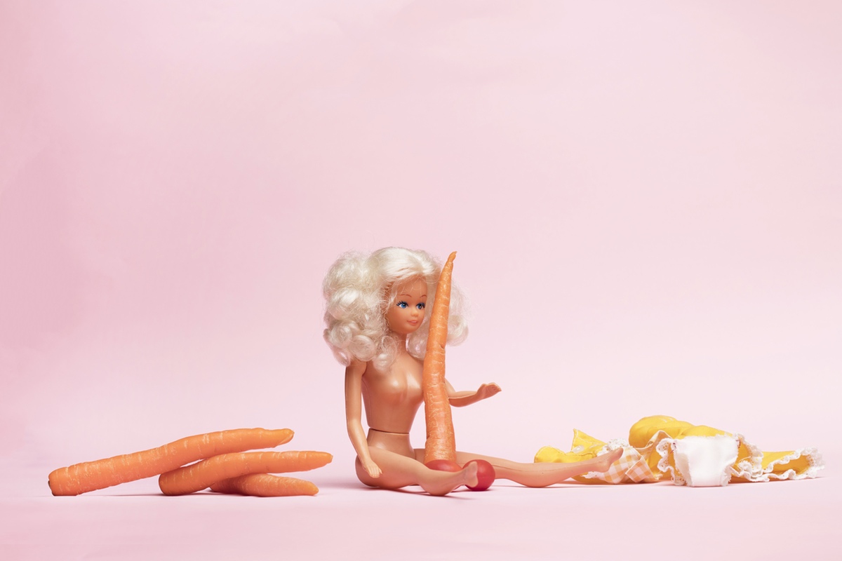 A naked Barbie doll surrounded by carrots to resemble penises.