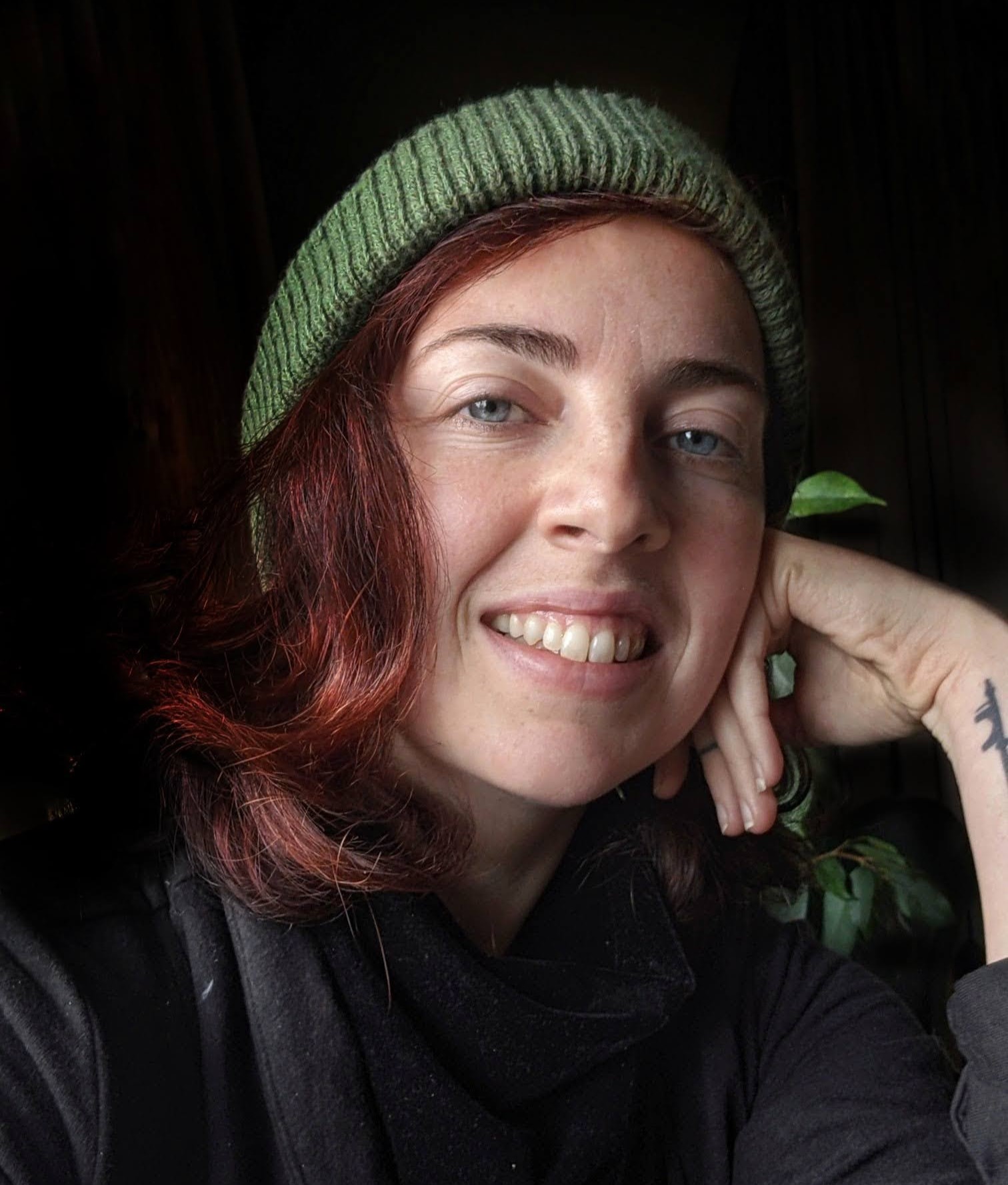 Kayla of the Midnight Rose Rebellion smiling at the camera and wearing a green beanie.