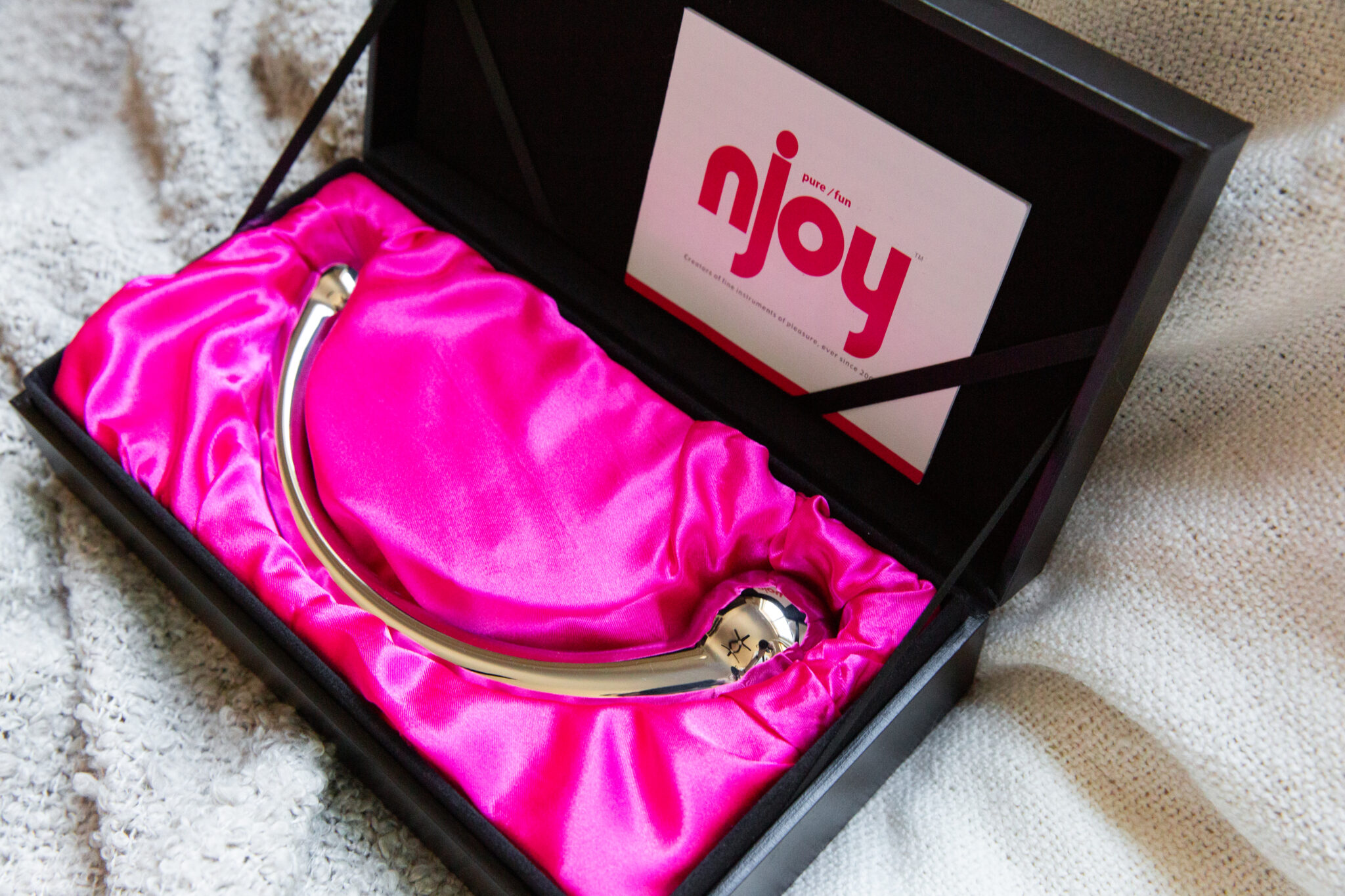 The njoy stainless steel dildo in its sleek, black and pink box.