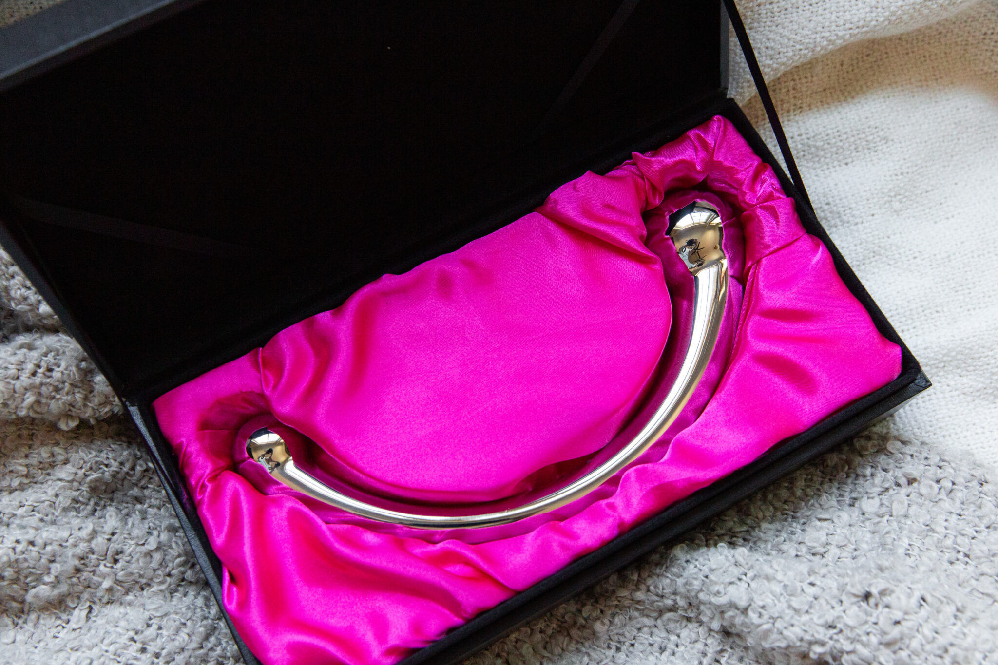 The njoy Pure Wand in its black box, resting on pink silk.