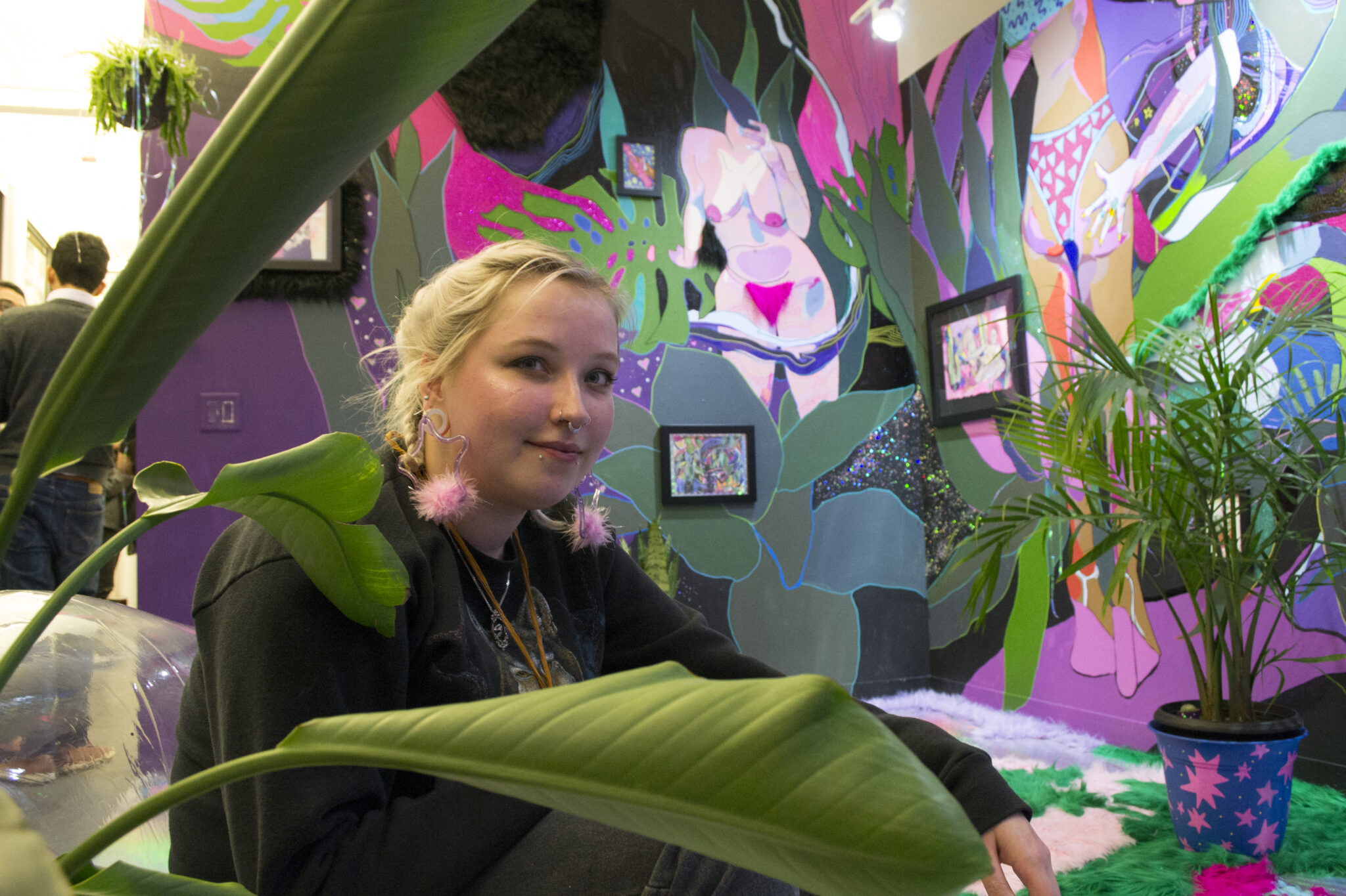 Headshot of artist Megan Wirick in a colorful studio full of art and plants.